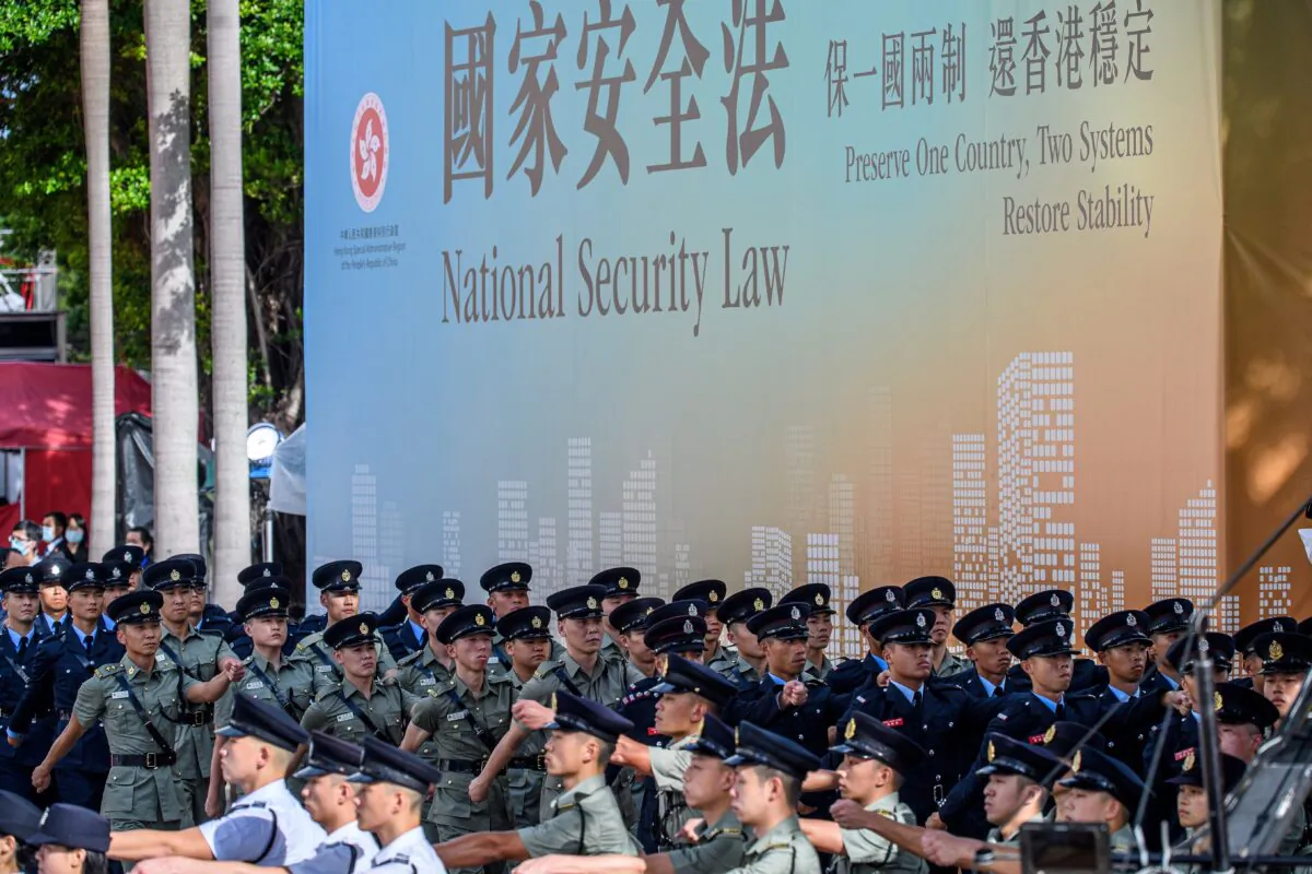 Attendees from various forces march next to a banner promoting the new national security law at the end of a flag-raising ceremony to mark the 23rd anniversary of Hong Kong's handover from Britain in Hong Kong on July 1, 2020. (Anthony Wallace/AFP via Getty Images)