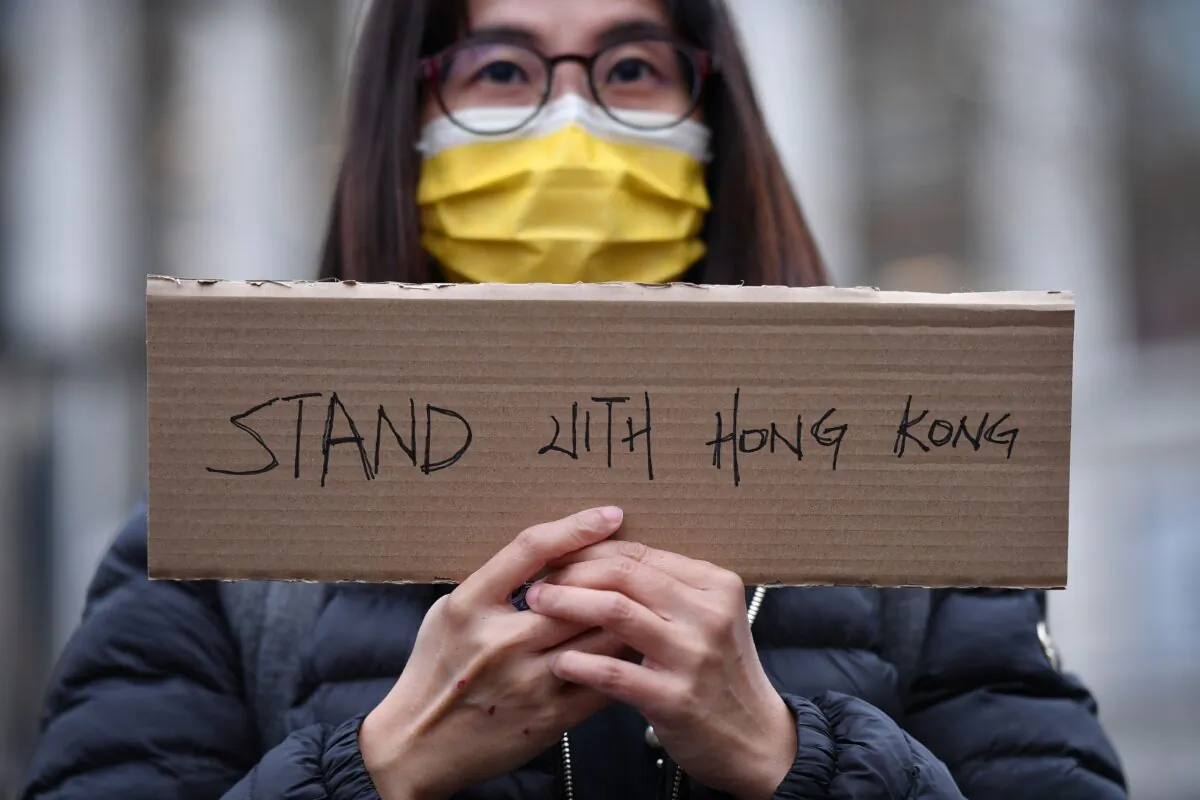 A protester holds a small placard at an event organised by Justitia Hong Kong to mourn the loss of Hong Kong's political freedoms, in Leicester Square, central London on Dec. 12, 2020. (Justin Tallis/AFP via Getty Images)