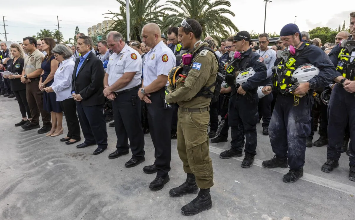 Miami-Dade County officials, members of search and rescue teams and Miami-Dade Fire Rescue along with police and workers who have been working at the site of the collapse, gather for a moment of prayer and silence in front of the rubble at the site of the Champlain Towers South condominium collapse in Surfside, Fla., on July 7, 2021. (Jose A Iglesias/Miami Herald via AP)