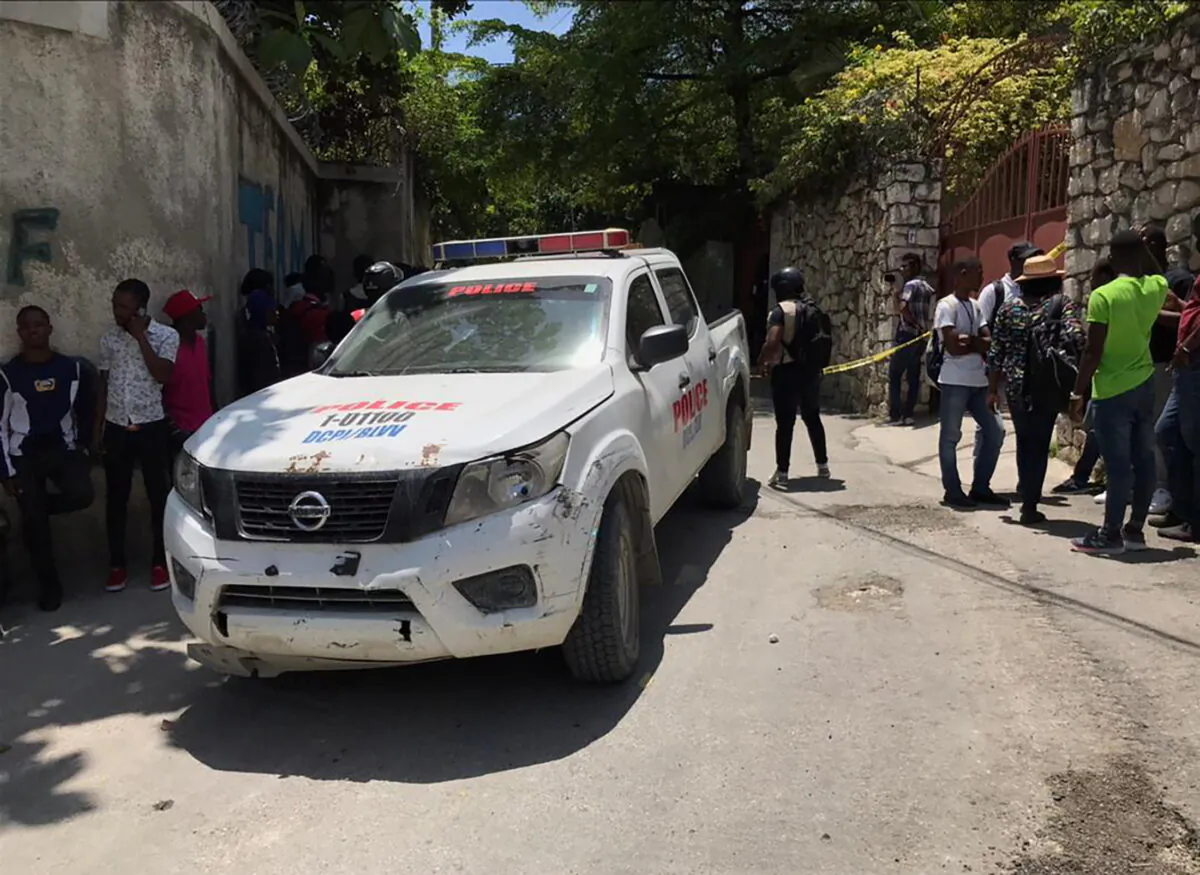People stand next to a police car and a yellow police cordon near the residence of Haiti's President Jovenel Moise after he was shot dead by unidentified attackers, in Port-au-Prince, Haiti, on July 7, 2021. (Estailove St-Val/Reuters)