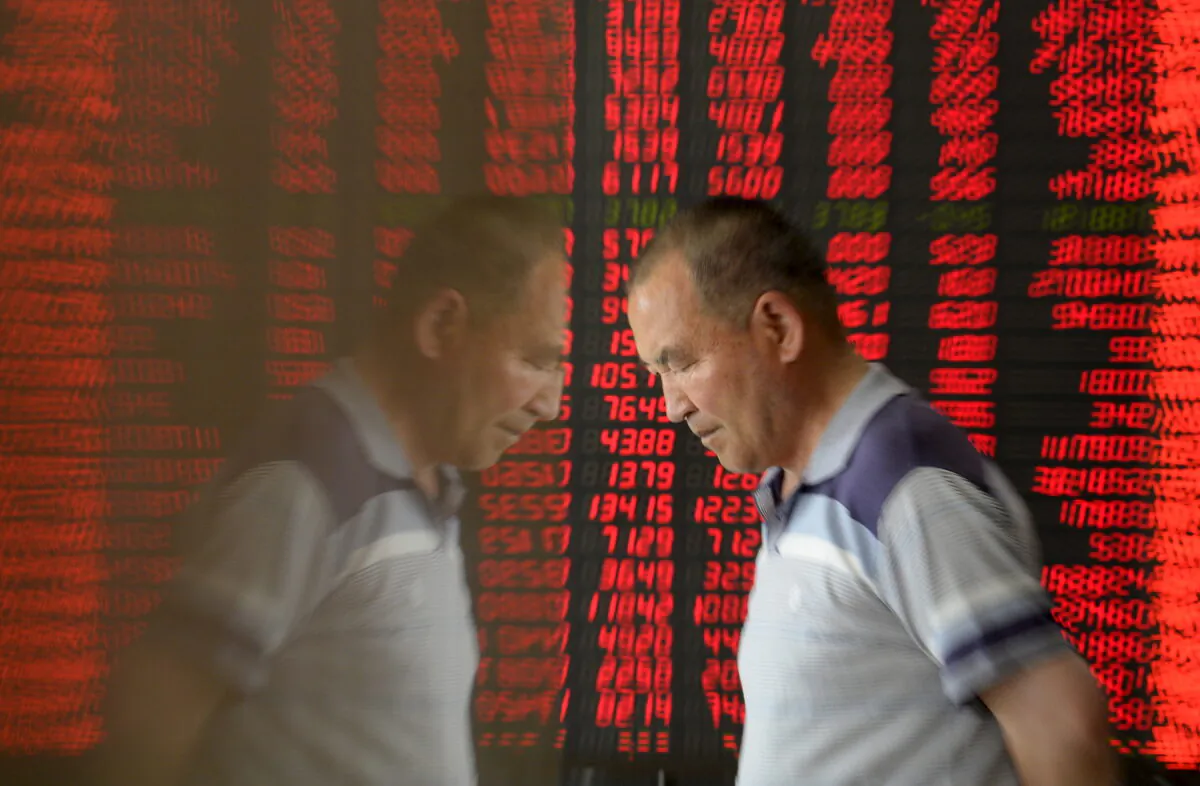 An investor is reflected on the surface of a wall as he walks past an electronic board showing stock information at a brokerage house in Taiyuan, Shanxi province, China, May 27, 2015 (Reuters/Jon Woo)
