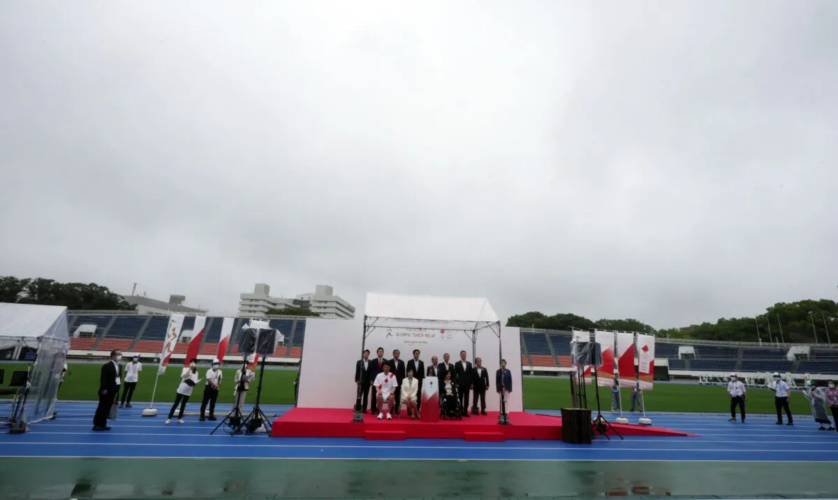 Guests pose for photographers during the unveiling ceremony for Olympic Flame of the Tokyo 2020 Olympic torch relay at empty Komazawa Olympic Park, in Tokyo, Japan, on July 9, 2021. (Eugene Hoshiko/AP Photo)
