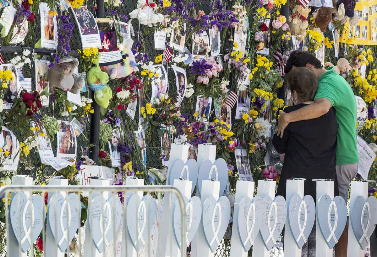 People mourn at the memorial wall for the victims of the Champlain Towers South collapse, in Surfside, Fla., on July 8, 2021. (Pedro Portal/Miami Herald via AP)