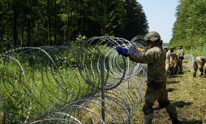 Lithuanian army soldiers install razor wire on border with Belarus in Druskininkai, Lithuania, on July 9, 2021. (Janis Laizans/Reuters)