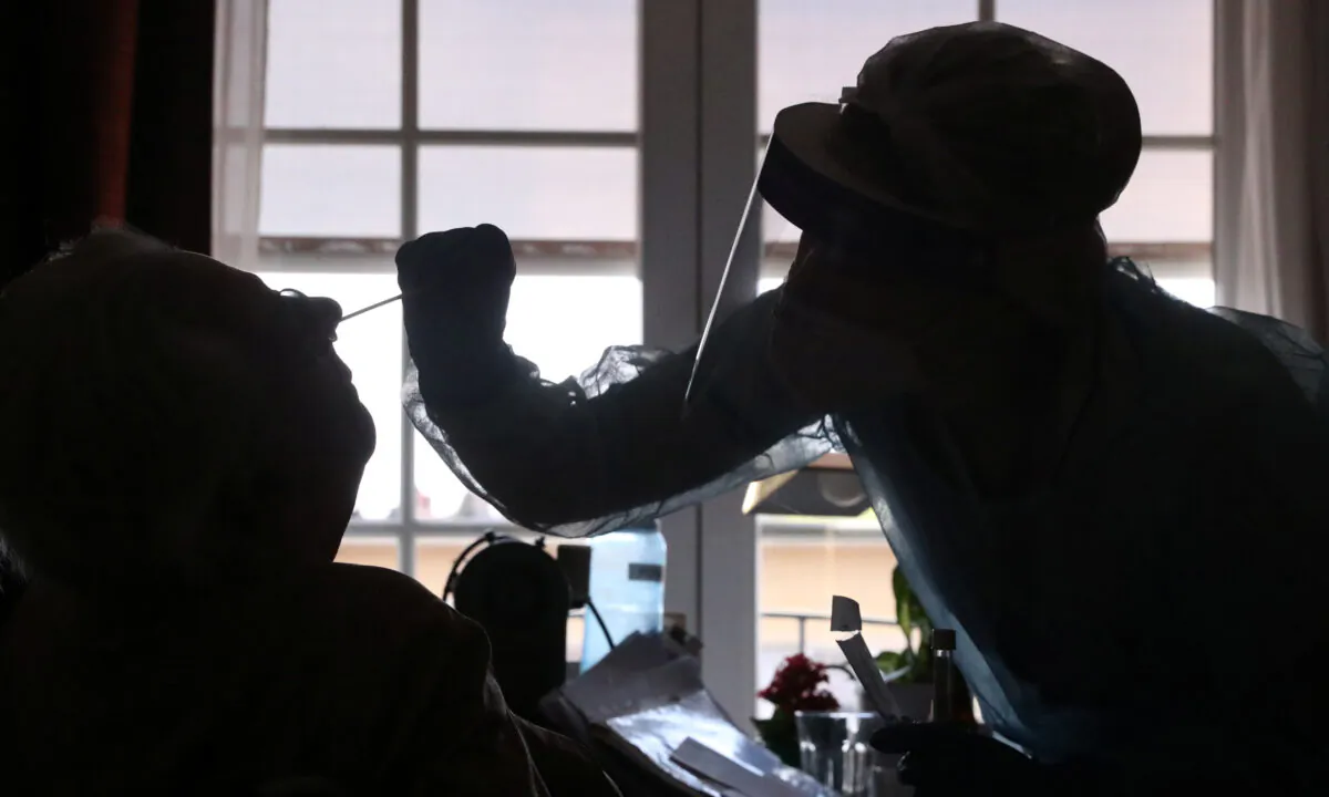 An employee at an elderly residence checks a person for CCP virus disease (COVID-19) in Brussels on April 16, 2020. (Yves Herman/Reuters)