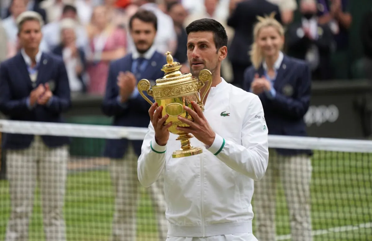 Serbia's Novak Djokovic celebrates holds his winner's trophy and celebrates his victory over Italy's Matteo Berrettini during the men's singles final match on day thirteen of the Wimbledon Tennis Championships in London, England, on July 11, 2021. (Alberto Pezzali/AP Photo)