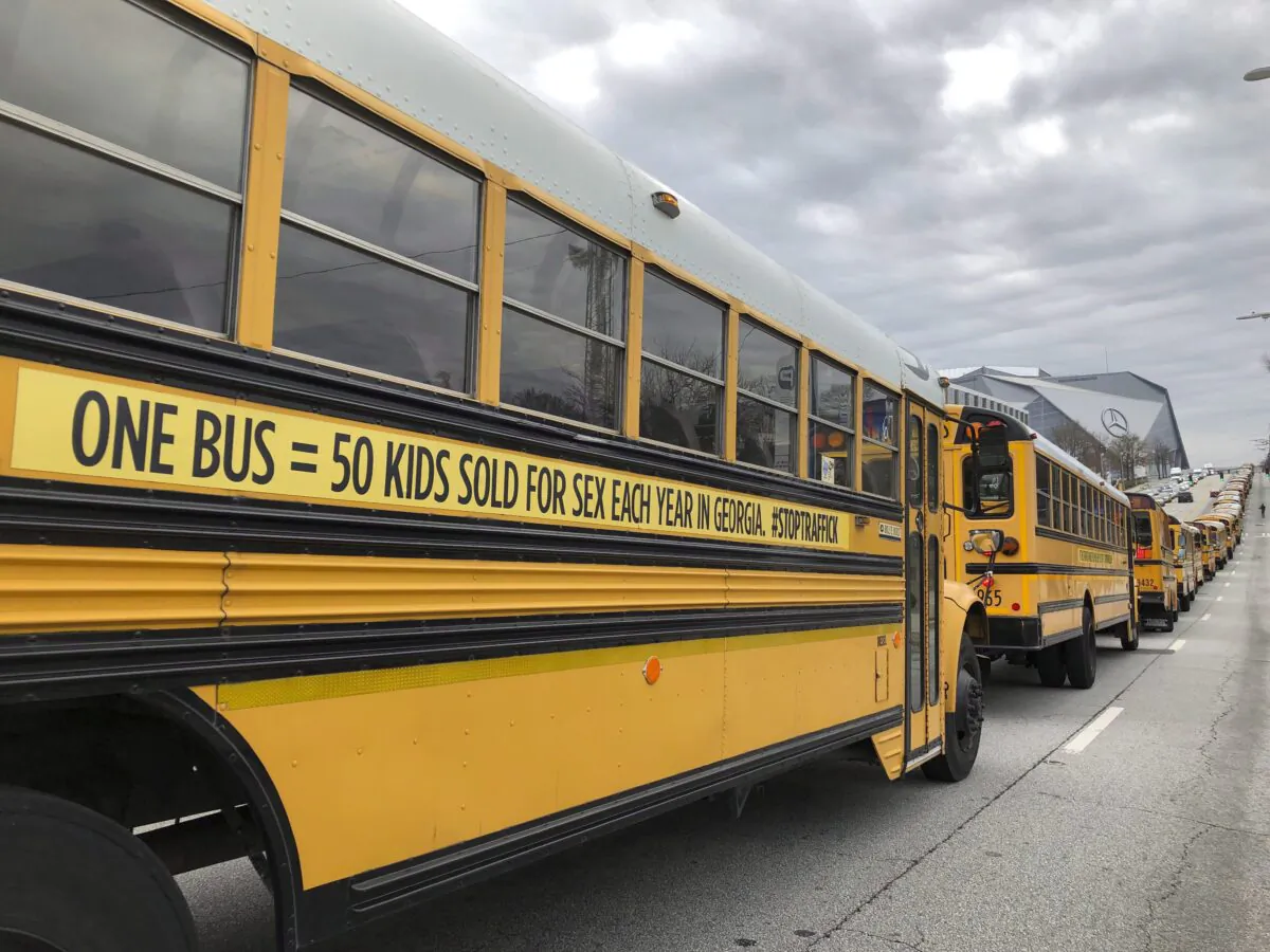A line of school buses with decals to draw attention to human trafficking make their way along a road in Atlanta, Georgia, on Jan. 2, 2019. (AP Photo/Sarah Morgan)
