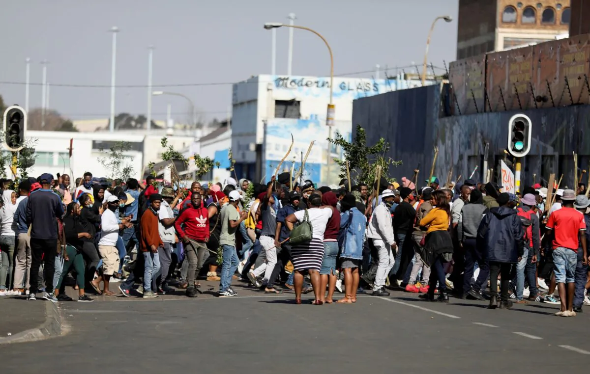 Stick-wielding rioters and looters march through the streets in Johannesburg, South Africa, on July 11, 2021. (Sumaya Hisham/Reuters)