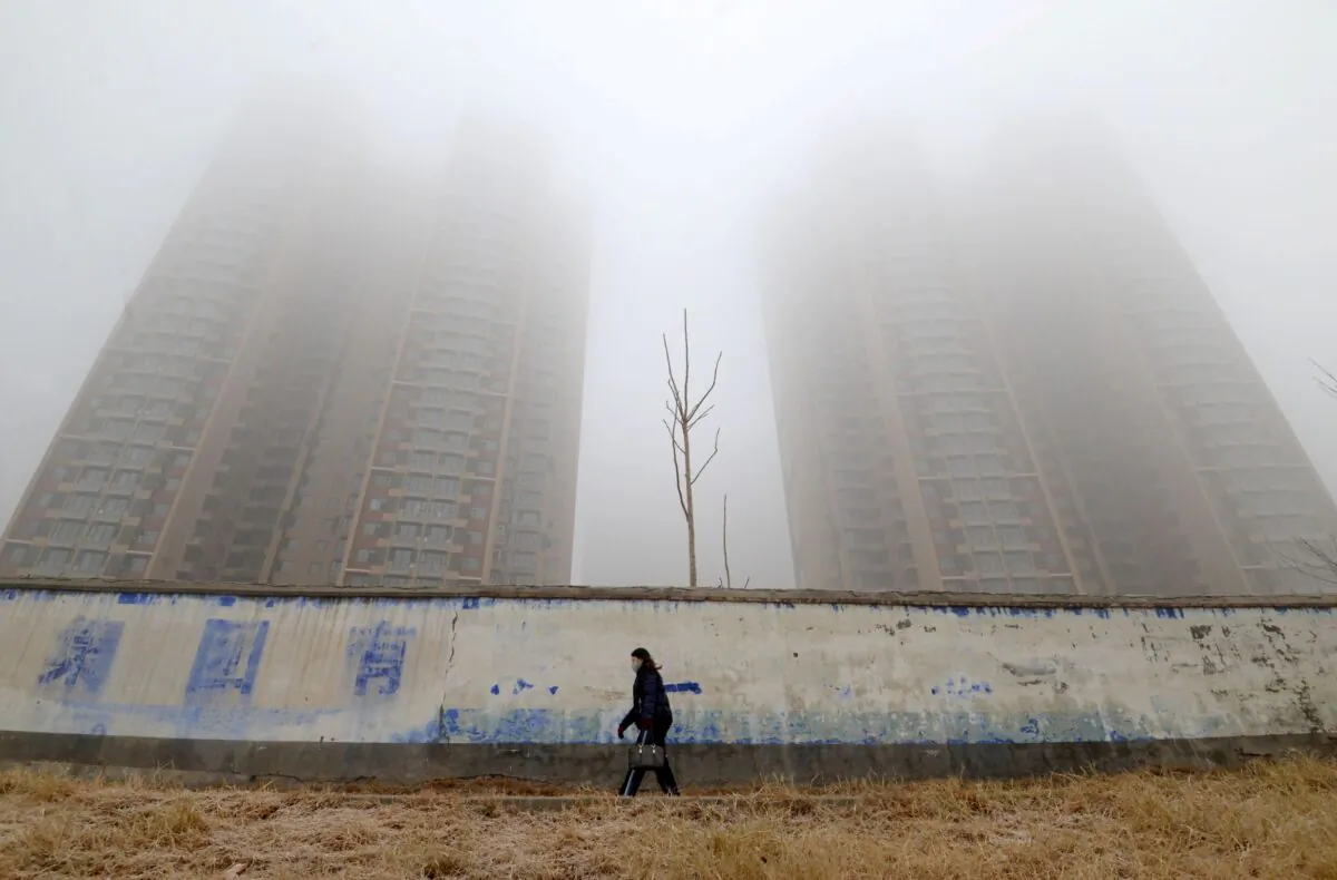 A woman wearing a mask walks past buildings on a polluted day in Handan, Hebei province, China, on Jan. 12, 2019. (Stringer/Reuters)