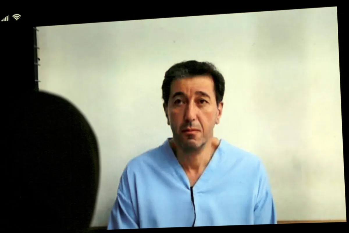 Bassem Awadallah, one of two former officials accused of helping Jordanian Prince Hamzah try to overthrow his half-brother King Abdullah II, appears on a mobile phone screen as he attends a verdict hearing at a state security court, in Amman, Jordan, on July 12, 2021. (Raad Adayleh/AP Photo)