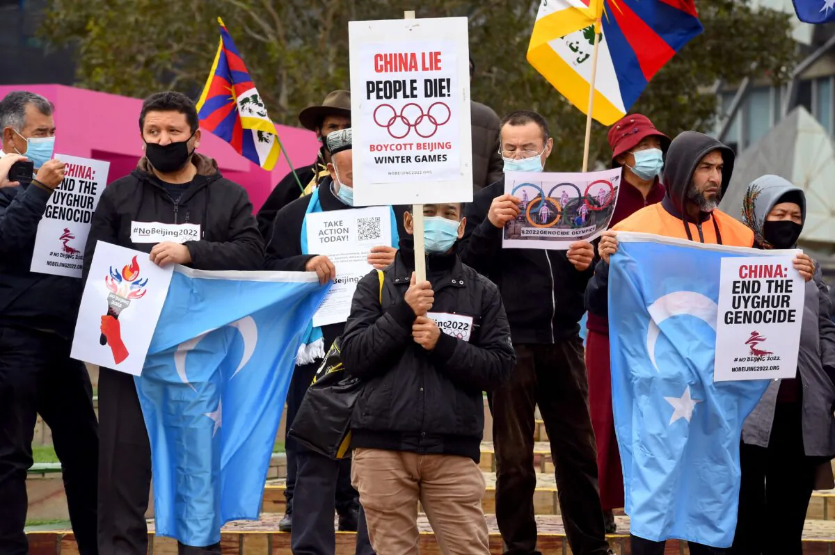 Activists, including members of the local Hong Kong, Tibetan, and Uyghur communities, hold up banners and placards calling on the Australian government to boycott the 2022 Beijing Winter Olympics over China's human rights record, in Melbourne, Australia, on June 23, 2021. (William West/AFP via Getty Images)