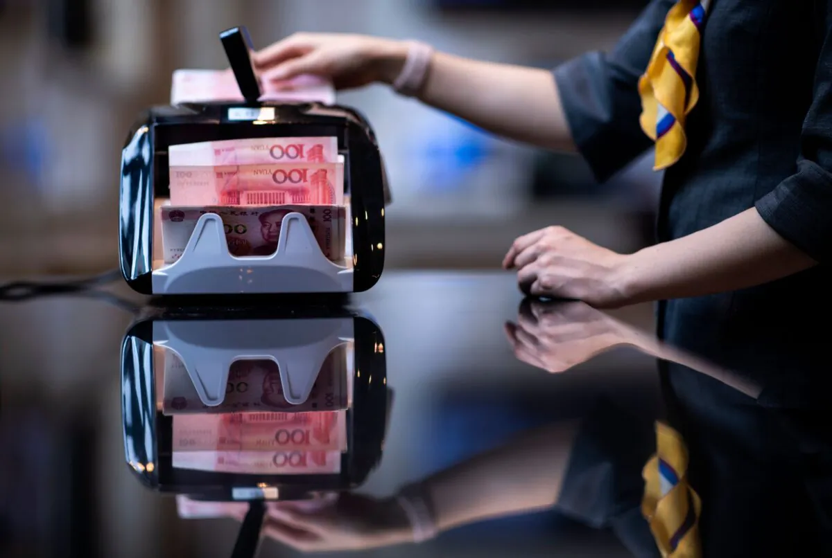 A bank employee uses a money counting machine to count out 100 yuan notes at a bank in Shanghai, China, in a file photo. (Johannes Eisele/AFP via Getty Images)