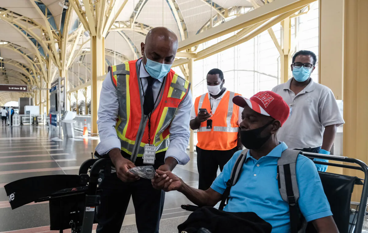 A Delta Airline employee gives a face mask to a passenger during check-in at the Ronald Reagan National Airport in Arlington, Va., on July 22, 2020. (Michael A. McCoy/Getty Images)