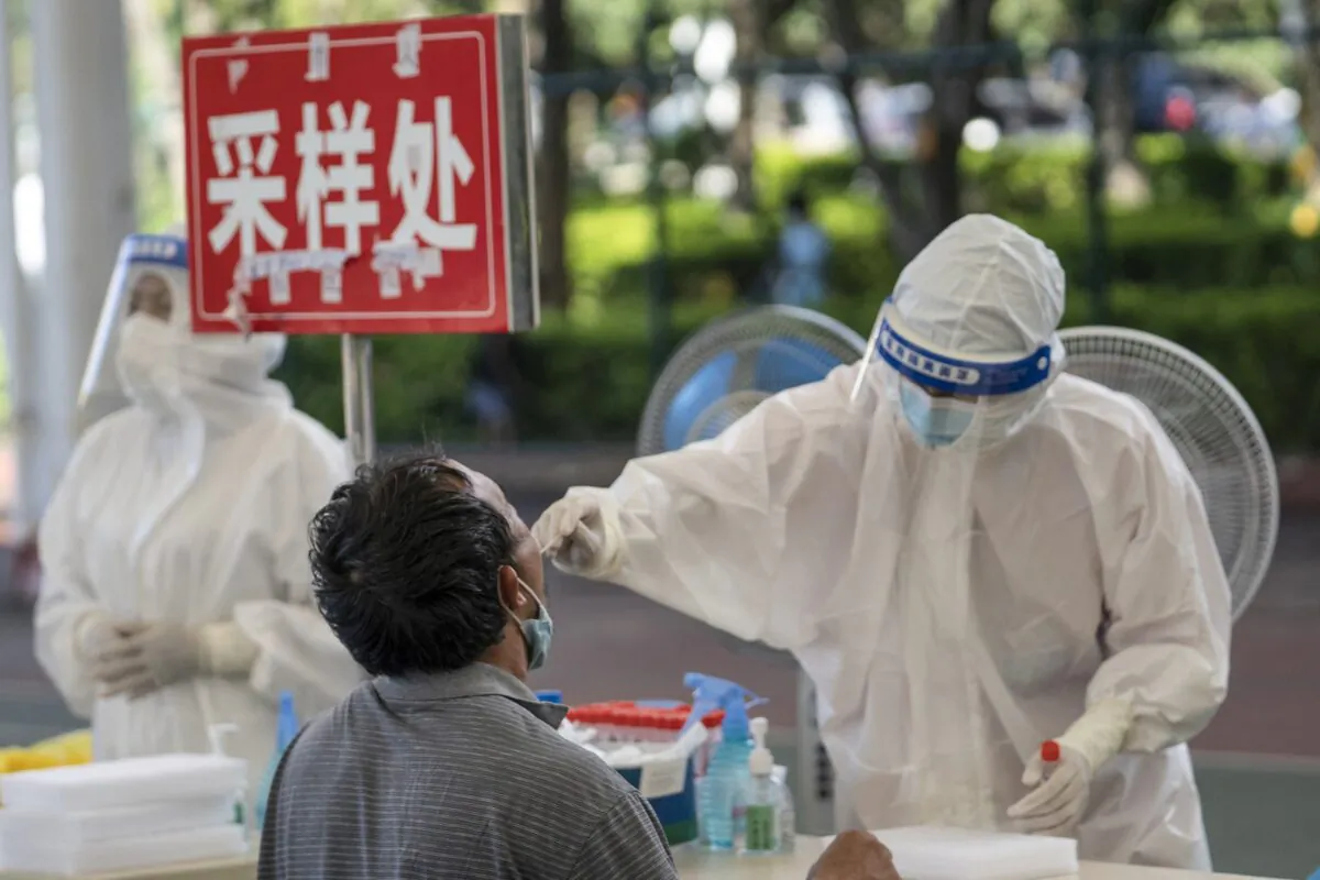 A man (L) is given a nucleic acid test for the Covid-19 coronavirus in Mangshi in the Dehong Dai and Jingpo Autonomous Prefecture, which borders Myanmar in China's southwestern Yunnan Province, on July 9, 2021. (STR/AFP via Getty Images)