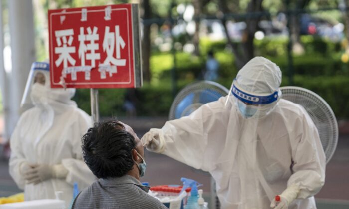 A man (L) is given a nucleic acid test for the Covid-19 coronavirus in Mangshi in the Dehong Dai and Jingpo Autonomous Prefecture, which borders Myanmar in China's southwestern Yunnan Province, on July 9, 2021. (STR/AFP via Getty Images)