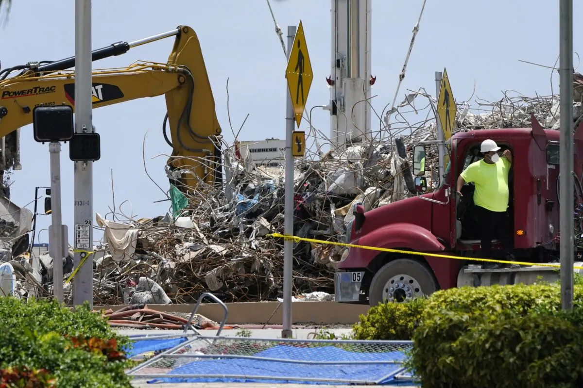A worker waits to load his truck with debris from the rubble of the Champlain Towers South building, as removal and recovery work continues at the site of the partially collapsed condo building in Surfside, Fla., on July 14, 2021. (Lynne Sladky/AP Photo)