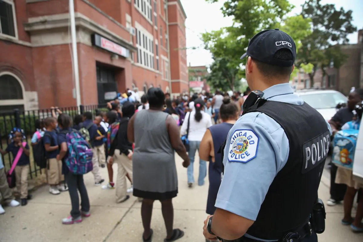 Chicago Probationary Police officer Juan Soto watches as students leave Laura Ward Elementary School on Chicago's West Side, on Aug. 28, 2013. (Photo by Scott Olson/Getty Images)