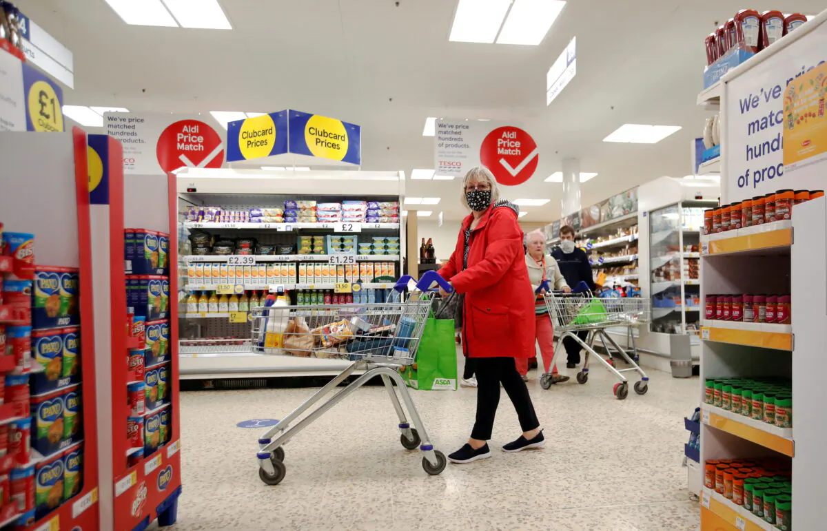 A woman wearing a mask pushes a shopping cart at a Tesco supermarket in Hatfield, United Kingdom, on Oct. 6, 2020. (Peter Cziborra/Reuters)
