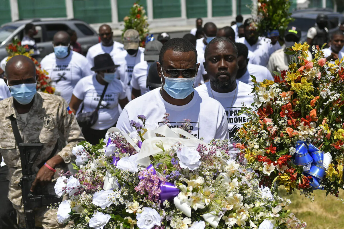 Men carry flowers to a spot outside the presidential palace in memory of slain President Jovenel Moise in Port-au-Prince, Haiti, on July 14, 2021. (Matias Delacroix/(AP Photo)