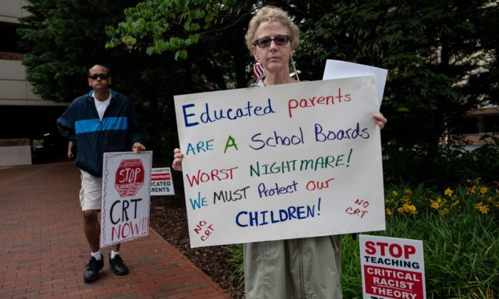 People hold up signs during a rally against critical race theory (CRT) being taught in schools at the Loudoun County Government Center in Leesburg, Va., on June 12, 2021. (Andrew Caballero-Reynolds/AFP via Getty Images)