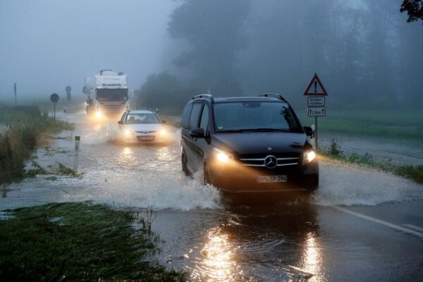 Vehicles travel on a flood affected road