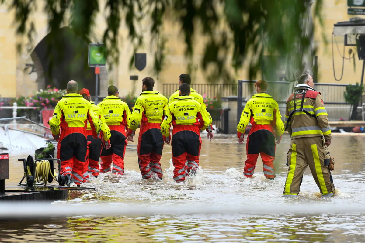 Lifeguards walk through a flooded street, following heavy rainfalls, in Valkenburg, Netherlands, July 15, 2021. (Piroschka Van De Wouw/Reuters)