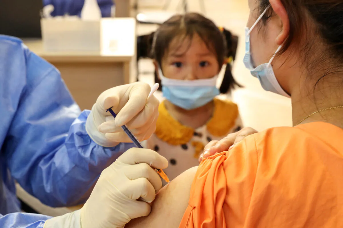 A child looks on as a woman receives the China National Biotec Group (CNBG) COVID-19 vaccine in Nantong, in China's eastern Jiangsu Province on July 5, 2021. (STR/AFP via Getty Images)