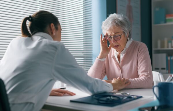 Caring doctor assisting a senior patient in her office