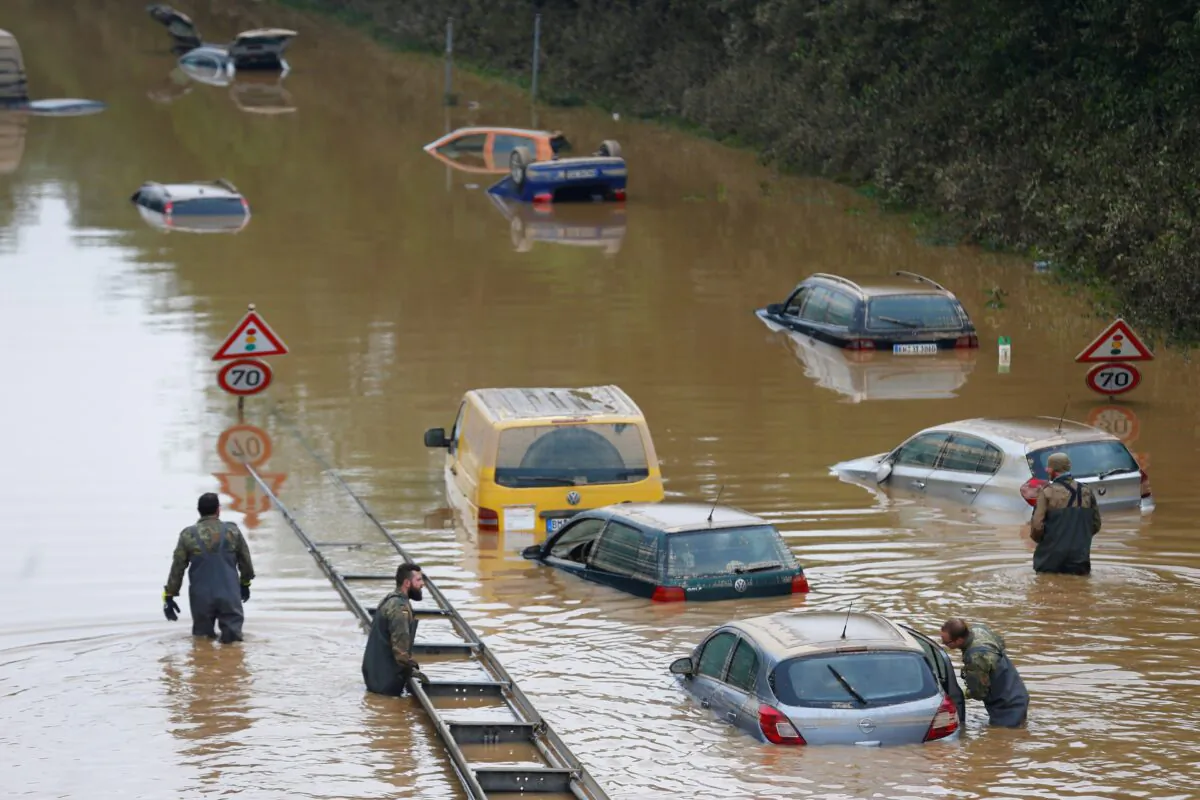 Members of the Bundeswehr forces, surrounded by partially submerged cars, wade through the flood water following heavy rainfalls in Erftstadt-Blessem, Germany, on July 17, 2021. (Thilo Schmuelgen /Reuters)