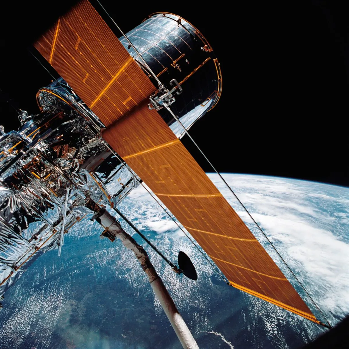 The giant Hubble Space Telescope can be seen as it is suspended in space by Discovery's Remote Manipulator System (RMS) following the deployment of part of its solar panels and antennae on April 25, 1990. (NASA via AP)