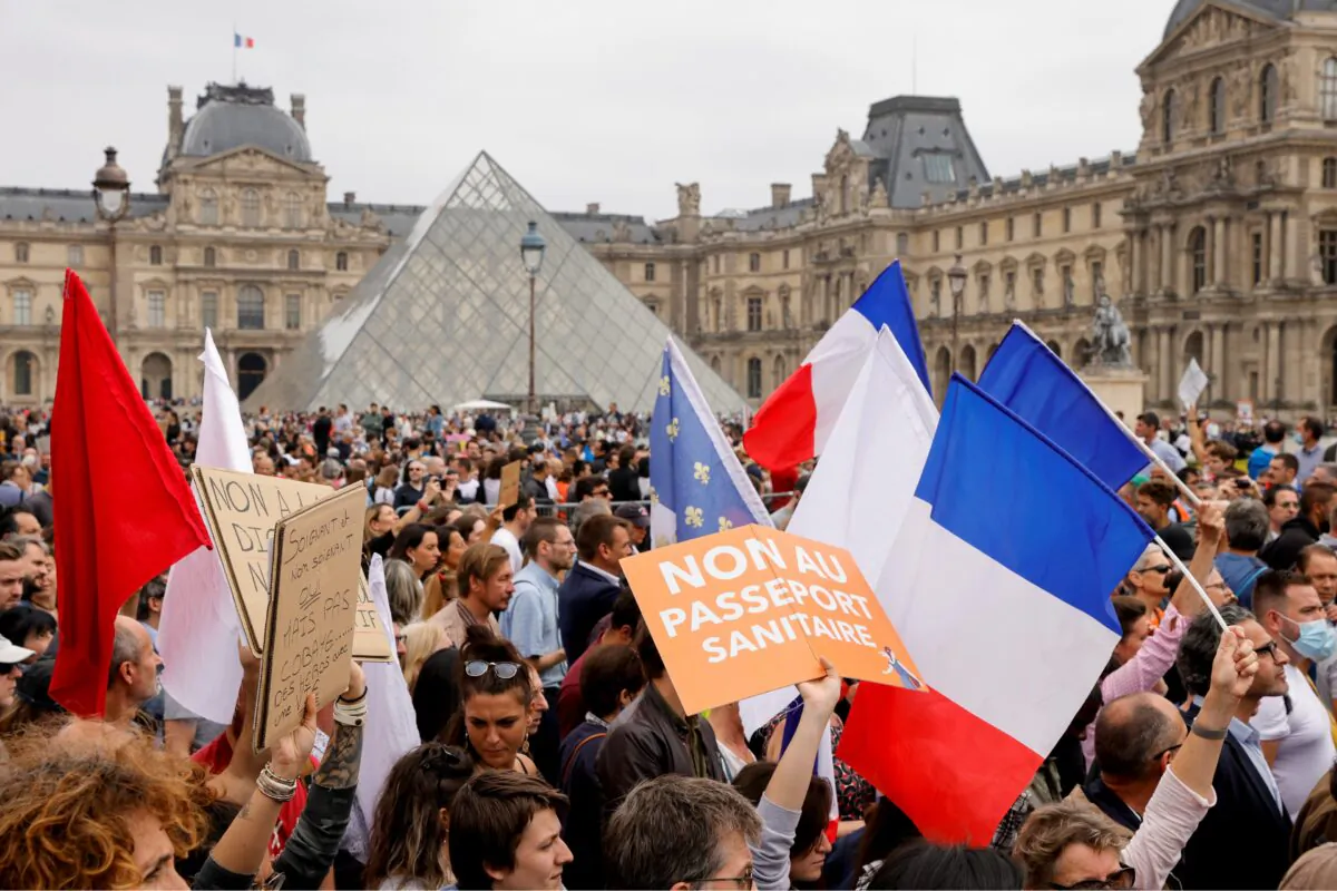 Demonstrators walk past Pyramide du Louvre during a protest against the new measures announced by French President Emmanuel Macron to fight the coronavirus disease (COVID-19) outbreak, in Paris, on July 17, 2021. (Pascal Rossignol /Reuters)