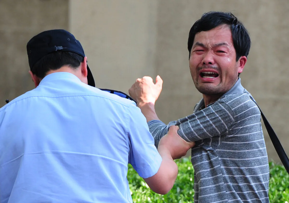 A police officer is detaining a petitioner, who is protesting about medical and land grab issues, outside the Chaoyang Hospital in Beijing, China on May 8, 2012. (Mark Ralston/AFP/Getty Images)