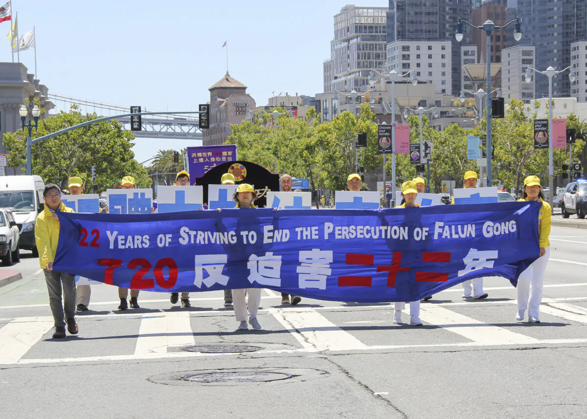 Falun Gong practitioners hold a banner calling for an end to the 22-year persecution of Falun Gong, during a parade in San Francisco on July 17, 2021. (Cynthia Cai/The Epoch Times)