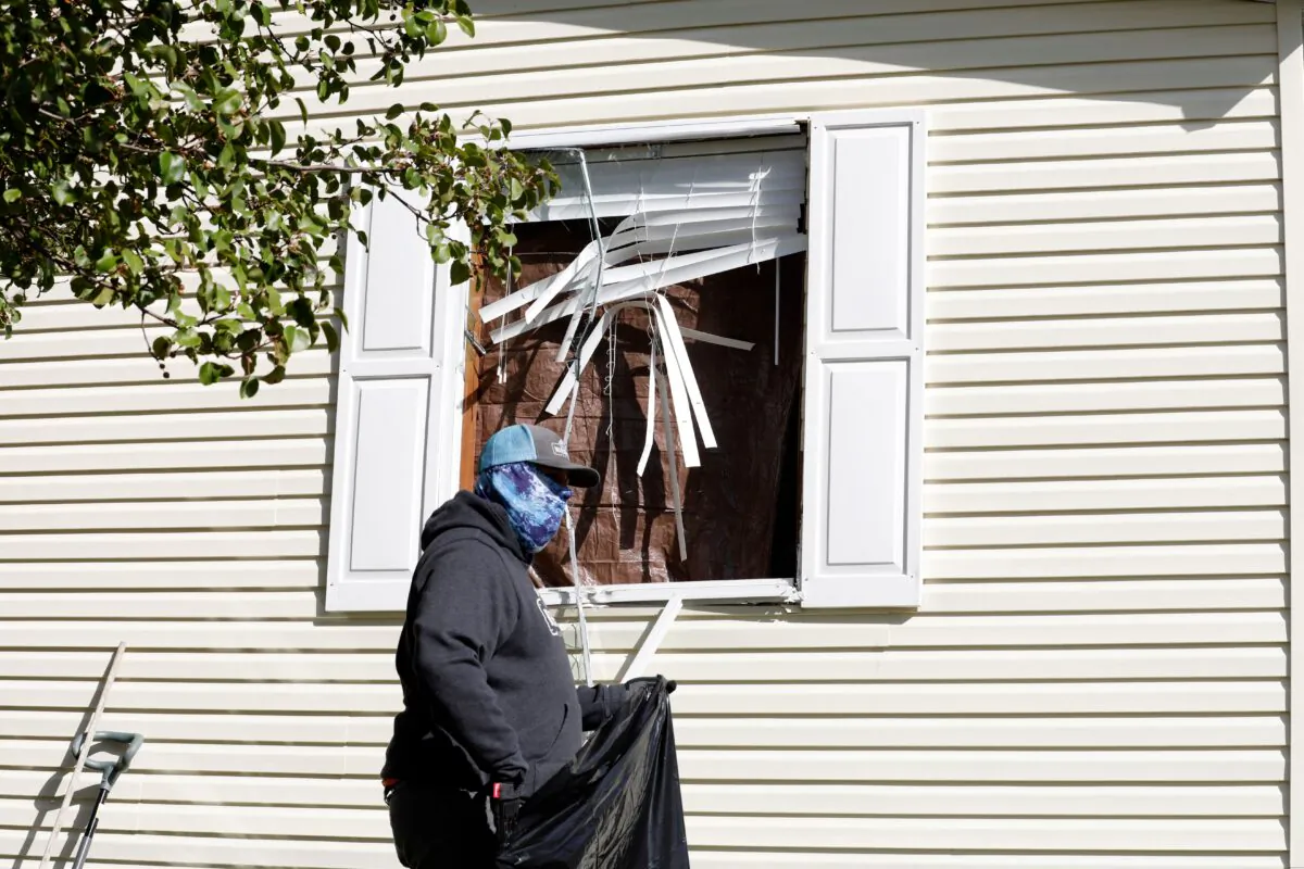 A person cleans up debris from a broken window at a home FBI agents searched in Hartland Township mobile home in connection of an alleged plot to kidnap Michigan Gov. Gretchen Whitmer, in Heartland, Mich., on Oct. 8, 2020. (Jeff Kowalsky/AFP via Getty Images)