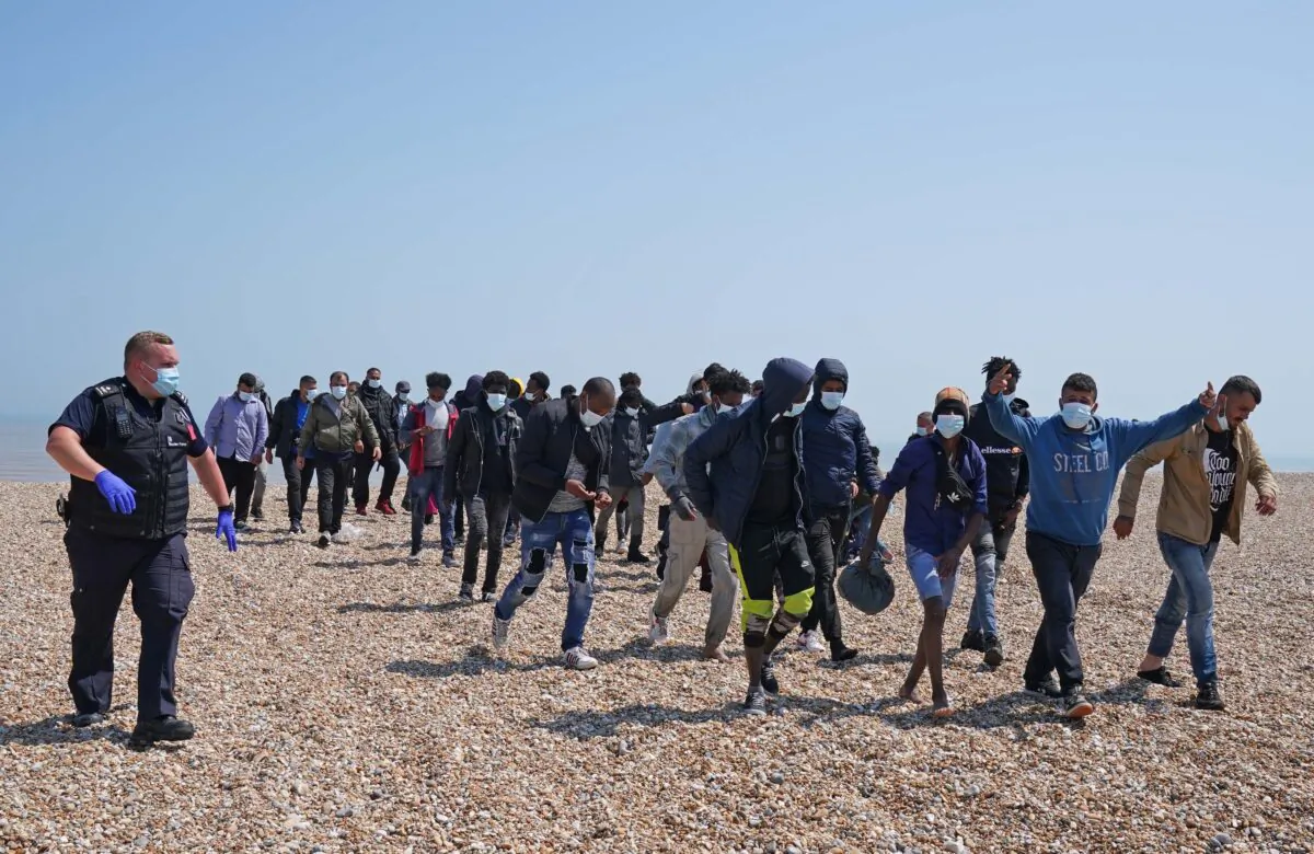 A group of people thought to be migrants are escorted by Border Force officers following a small boat incident in the Channel, from the beach in Dungeness, Kent, Britain, on July 20, 2021. (Gareth Fuller/PA)
