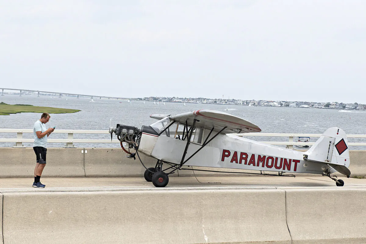Landon Lucas stands next to his plane after he made an emergency landing on the Route 52 causeway connecting Ocean City and Somers Point, N.J., on July 19, 2021. (Matthew Strabuk/The Press of Atlantic City via AP)