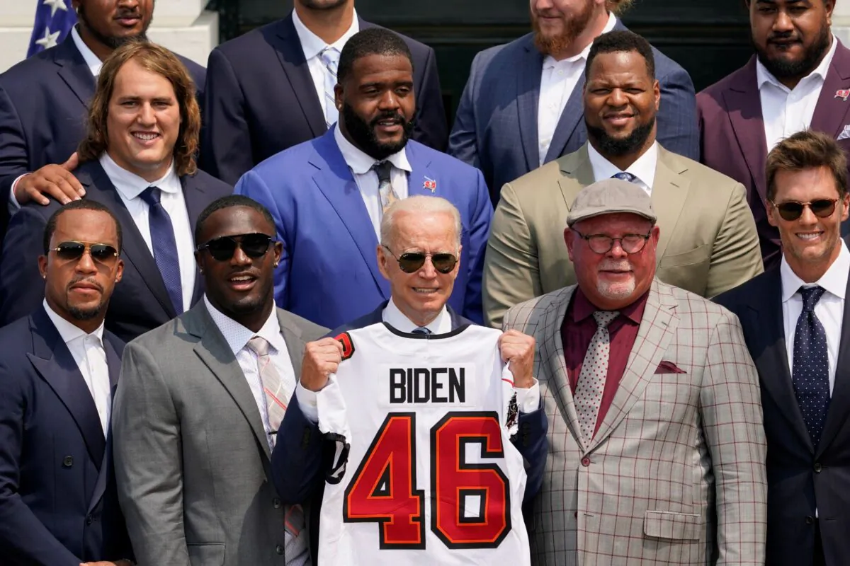 President Joe Biden, surrounded by members of the Tampa Bay Buccaneers, poses for a photo holding a jersey during a ceremony on the South Lawn of the White House, where Biden honored the Super Bowl Champion Tampa Bay Buccaneers for their Super Bowl LV victory, in Washington on July 20, 2021. (Andrew Harnik/AP Photo)