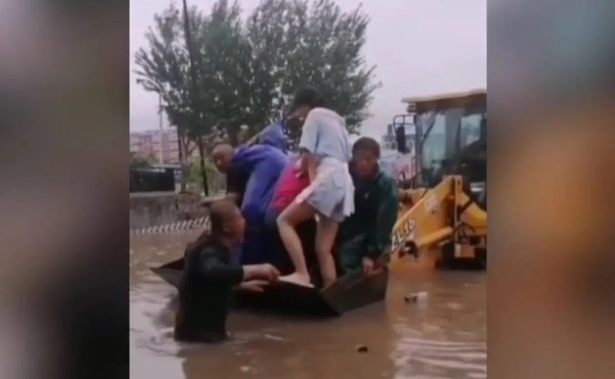 Man helping a woman get on the boat during flood in Inner Mongolia on July 2021. (Screenshot/NTD)