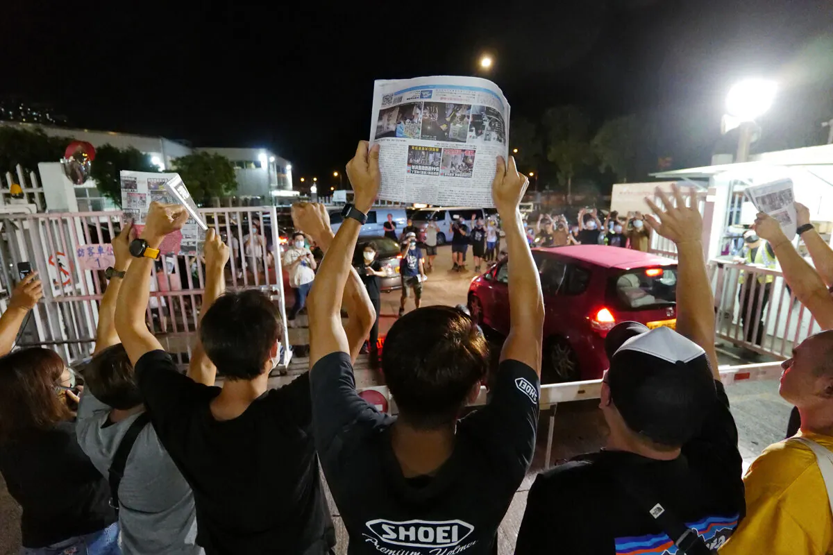Apple Daily journalists hold freshly-printed copies of the newspaper's last edition while acknowledging supporters gathered outside their office in Hong Kong early on June 24, 2021. The pro-democracy tabloid was forced to close after 26 years under a sweeping new national security law. (Daniel Suen/AFP via Getty Images)