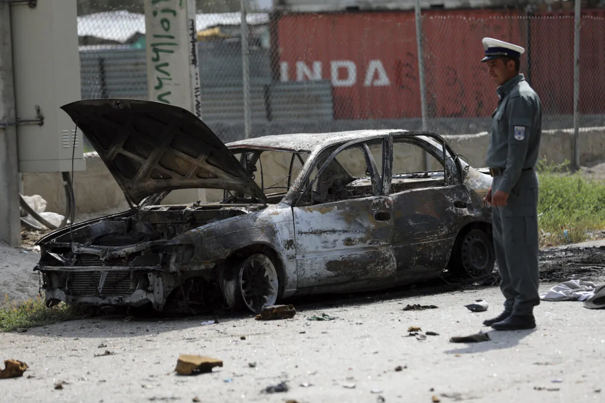 Afghan traffic police stand near a damaged vehicle where rockets were fired from in Kabul, Afghanistan, on July 20, 2021. (Rahmat Gul/AP Photo)