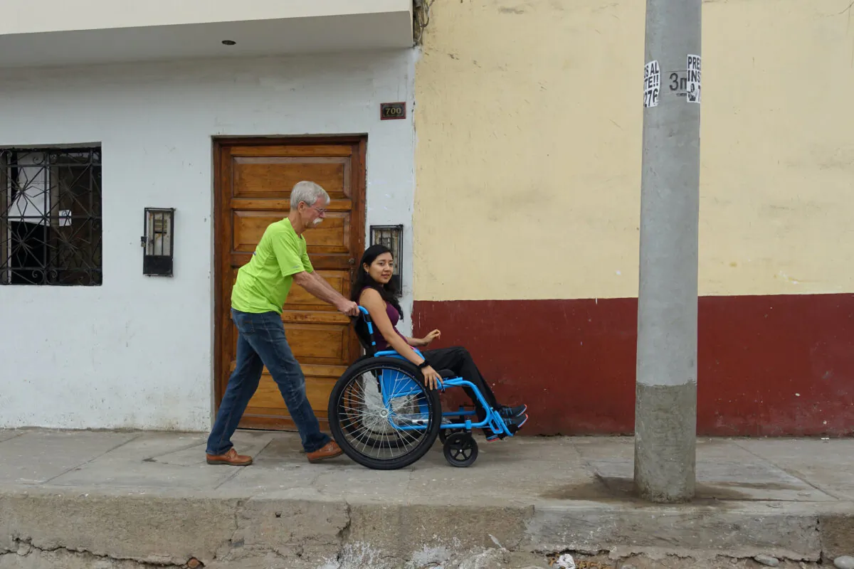 Free Wheelchair Mission founder Don Schoendorfer pushes a woman along a sidewalk. (Courtey of Don Schoendorfer)
