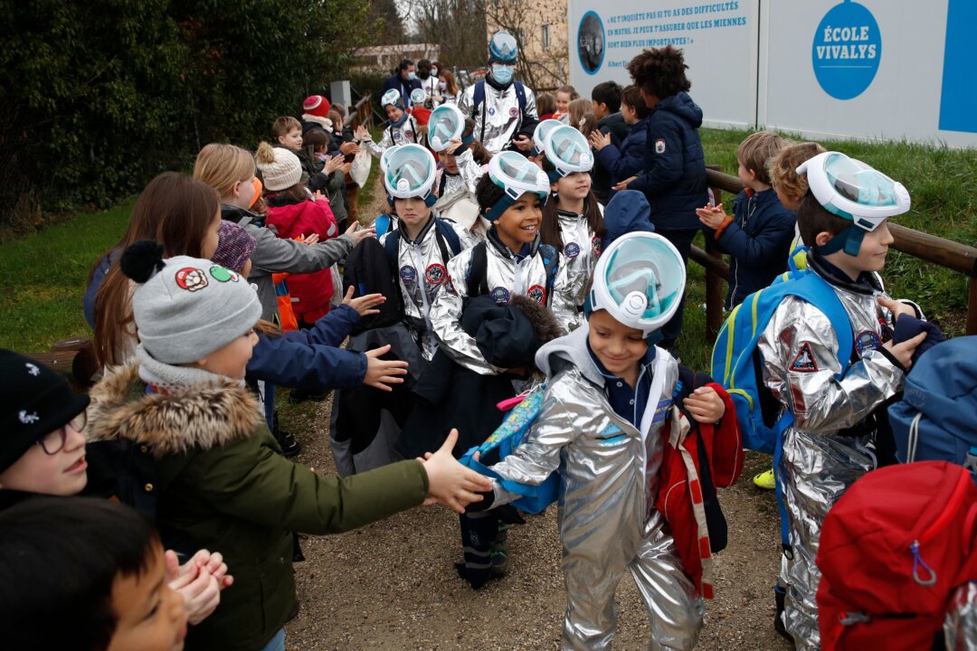 Children shake hands with pupils of the Ecole Vivalys elementary school, wearing spacesuits costumes, as they leave school during their project Mission to Mars in Lausanne, Switzerland, on March 17, 2021. (Stefan Wermuth/AFP via Getty Images)