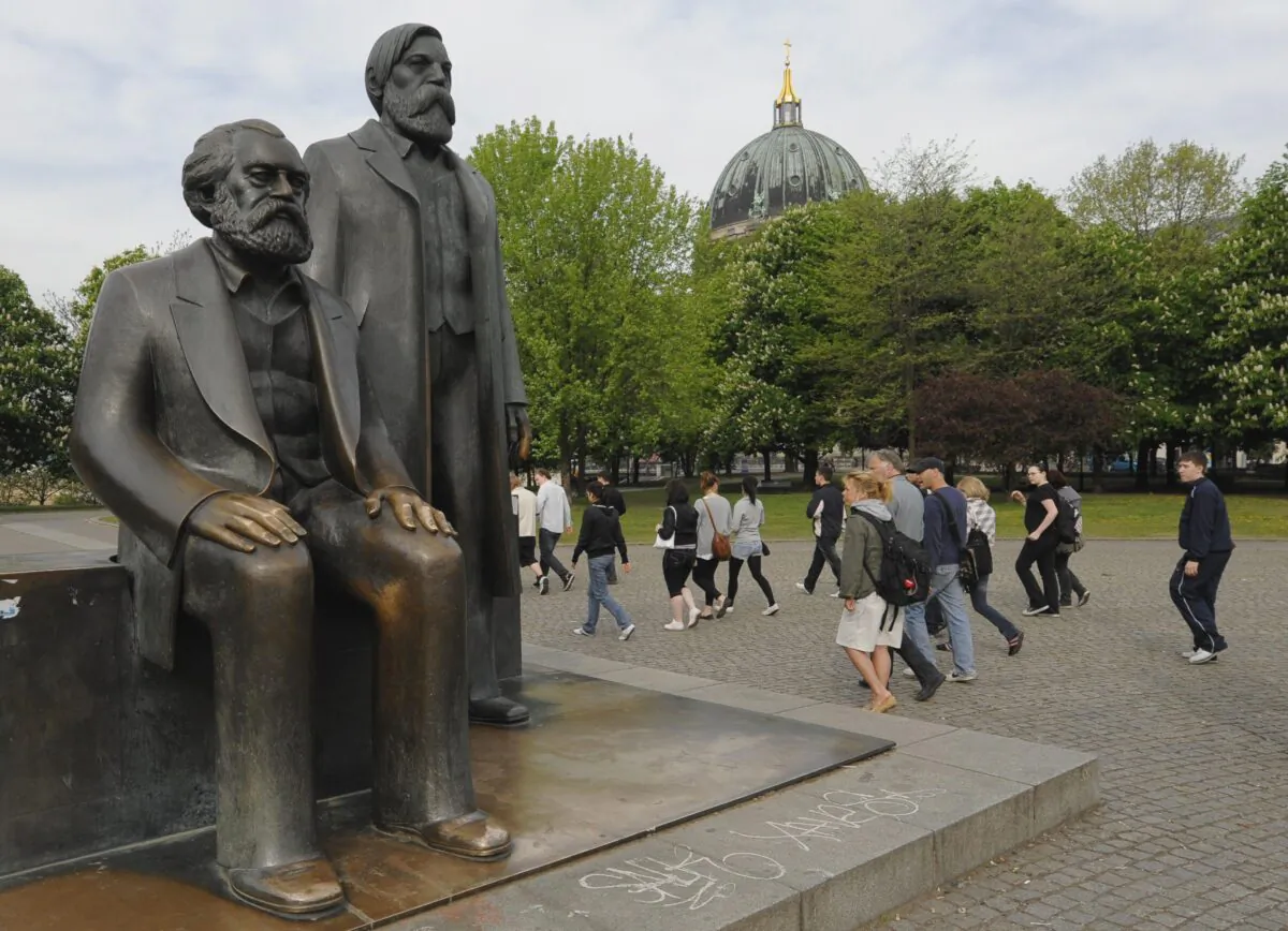 Tourists walk past a statues of Karl Marx (1818–83) and Friedrich Engels (1820–95) in the center of Berlin on April 28, 2009. (Theo Heimann /DDP/AFP via Getty Images)