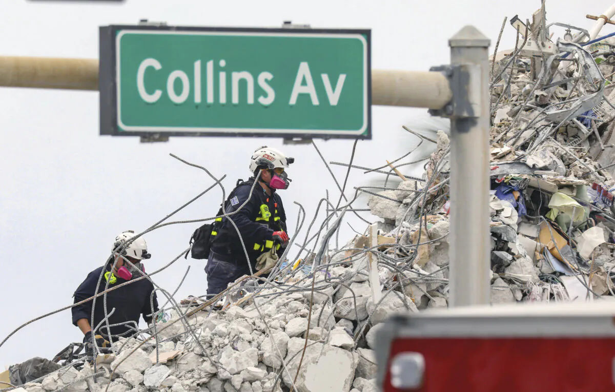 Search and rescue team members climb the debris field of the 12-story oceanfront condo, Champlain Towers South along Collins Avenue in Surfside, Fla., on July 7, 2021. (Al Diaz/Miami Herald via AP)