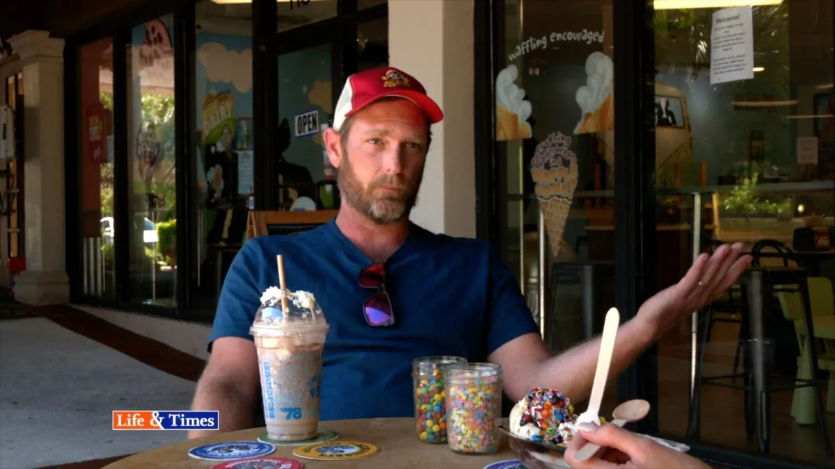 In a still image from a video released by NTD, Ben & Jerry’s franchise owner, Stephen Chubbuck, talks to NTD host, Kay Rubacek, about how he uses the social element of ice cream to get all members of the community to talk again. (Oliver Trey/NTD)