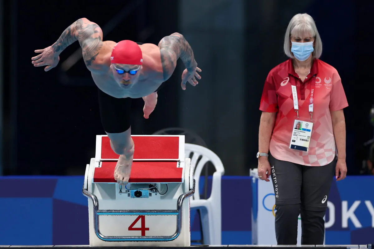 Adam Peaty of Britain in action as a referee wearing a mask looks on at Tokyo 2020 Olympics in Tokyo, Japan, on July 24, 2021. (Kai Pfaffenbach/ Reuters)