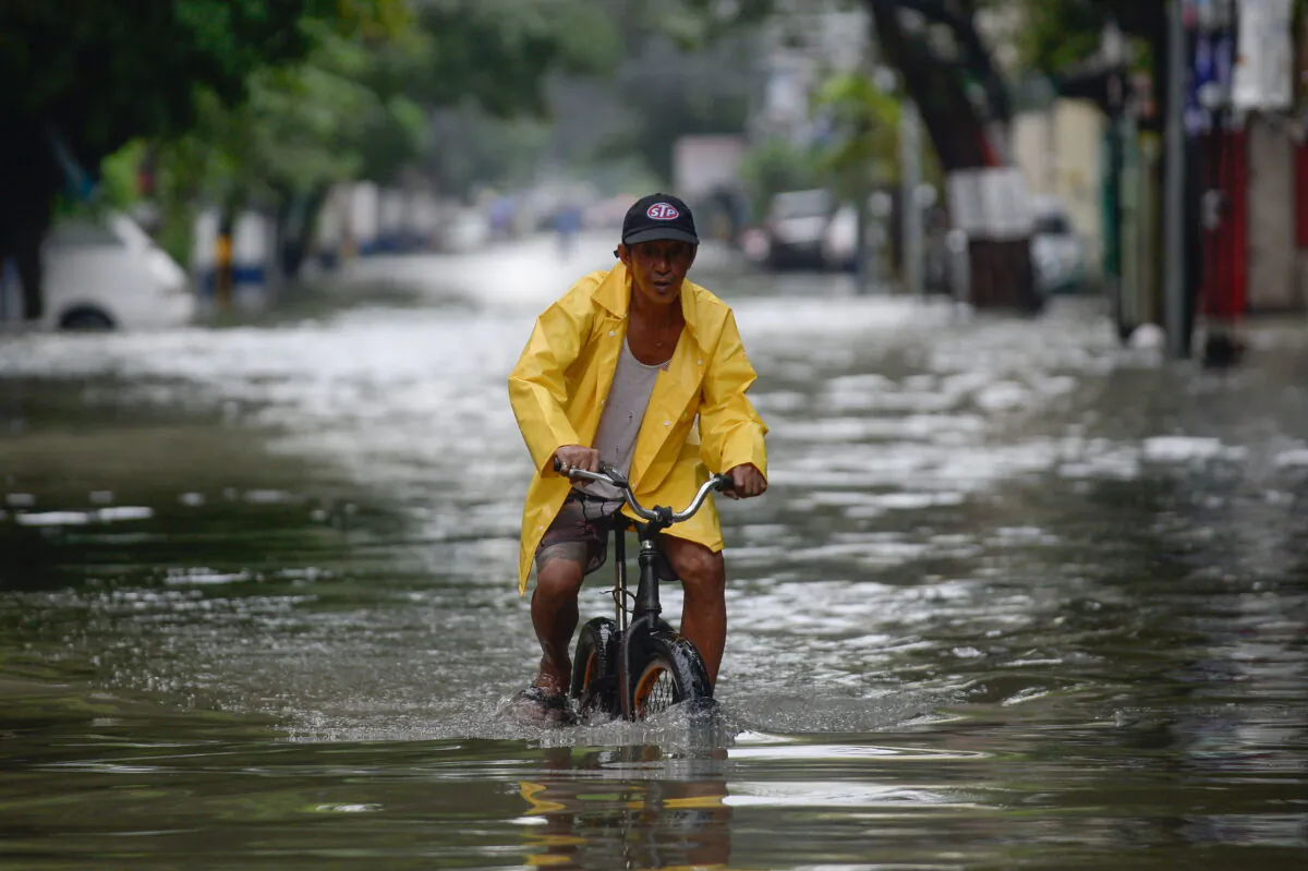 A man on a bicycle wades through a flooded street in Manila, Philippines, on July 24, 2021. (Lisa Marie David/Reuters)