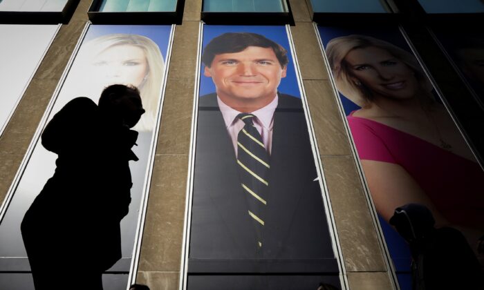 Människor passerar en marknadsföring av Fox News-värden Tucker Carlson i News Corporation-byggnaden i New York den 13 mars 2019. (Brendan McDermid/Reuters)