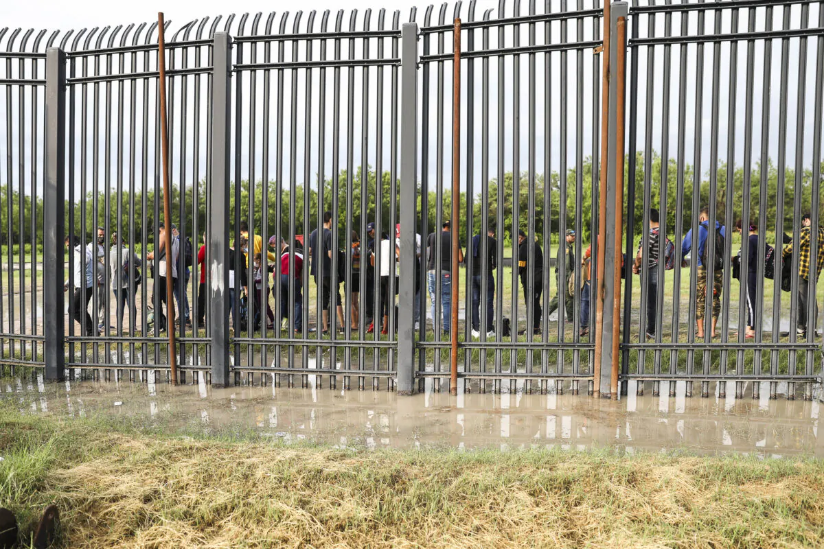 Illegal immigrants wait to be picked up by Border Patrol after crossing the Rio Grande from Mexico into Del Rio, Texas, on July 20, 2021. (Charlotte Cuthbertson/The Epoch Times)