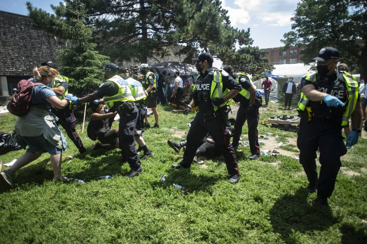Police remove encampment supporters as they clear the Lamport Stadium Park homeless camp in Toronto on July 21, 2021. (The Canadian Press/Chris Young)